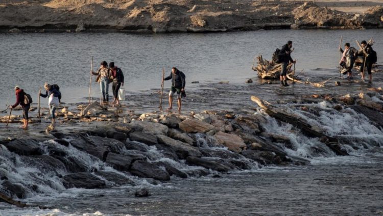 مهاجرون يقطعون نهر ميريك الذي يفصل بين تركيا واليونان (رويترز)